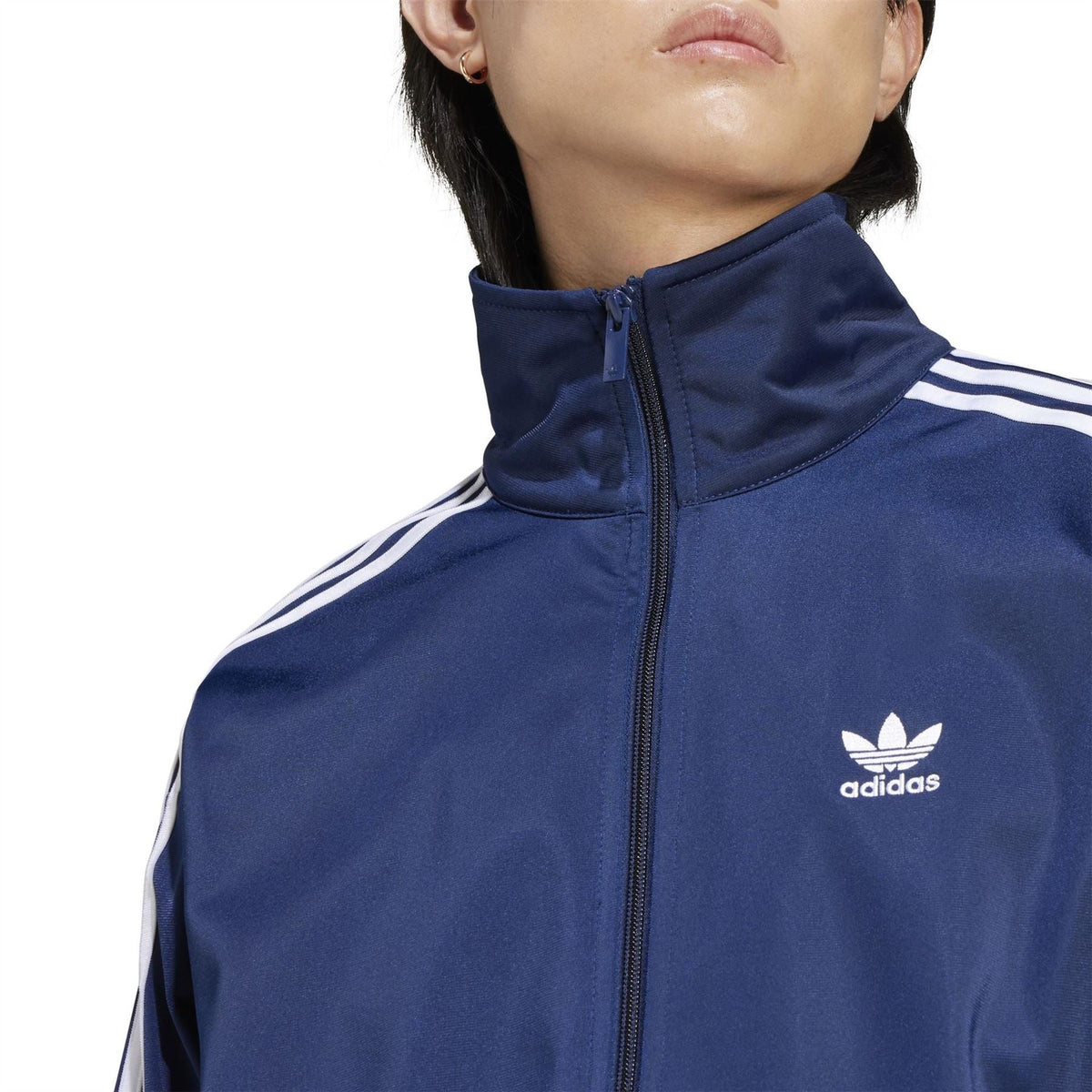 Men's indigo adidas track jacket close-up of logo, stand collar, and full zip