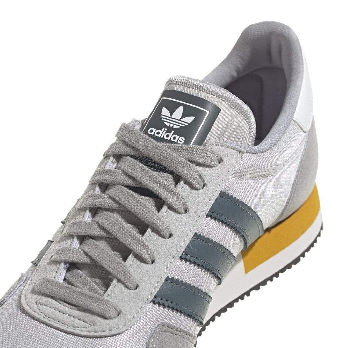 Close-up of light grey adidas USA 84 trainers with lace-up front and tongue logo