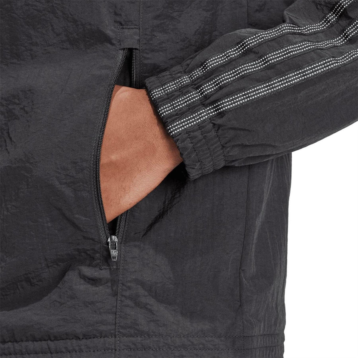 Black track jacket zipper and front seam detail with elasticized hem