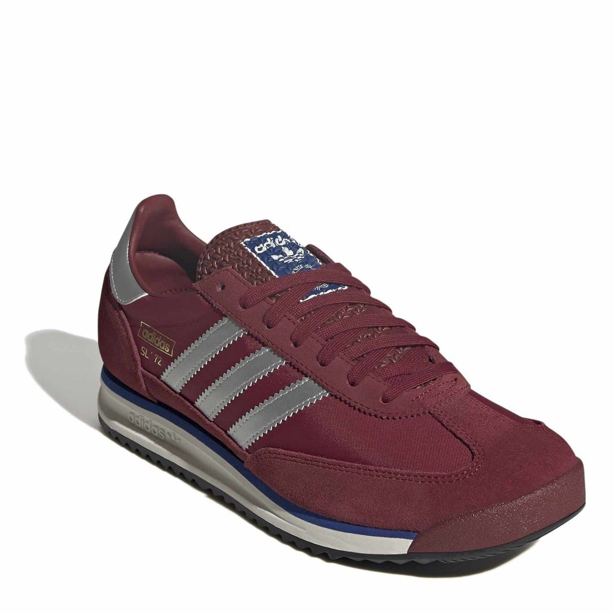 Burgundy sneakers with white stripes, textured tongue patch, and blue sole edge.