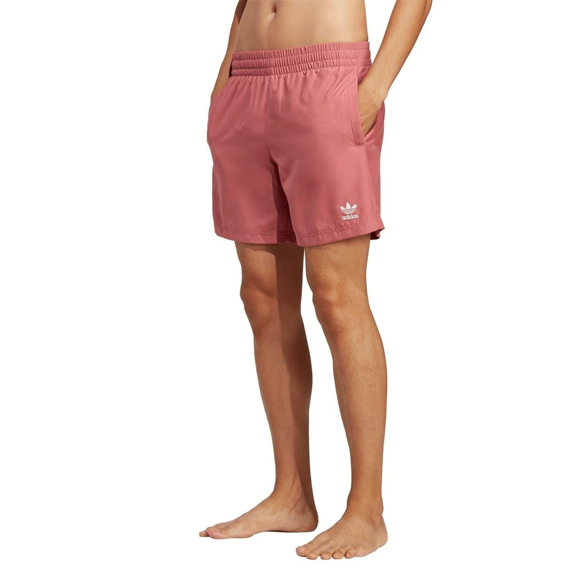 Pink swim shorts with elastic waistband and adidas logo, worn on legs