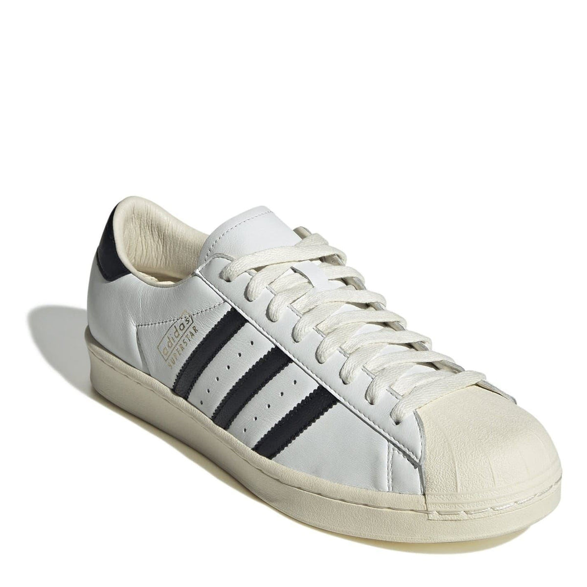 Cream-and-white sneakers with black heel patch, lace-up front, and padded collar