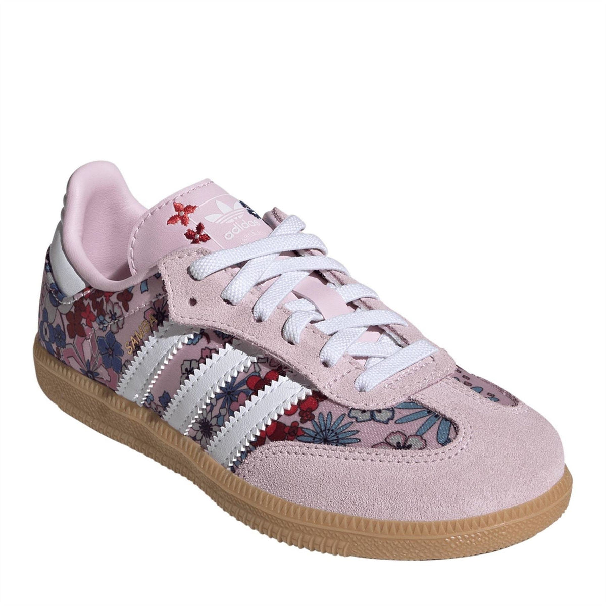 Pink suede low-top sneakers with floral side panels, white stripes, and lace-up.
