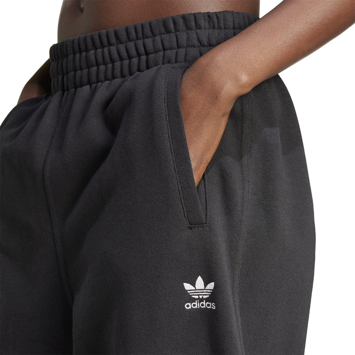 Black adidas Originals joggers closeup: ribbed waistband and small adidas logo