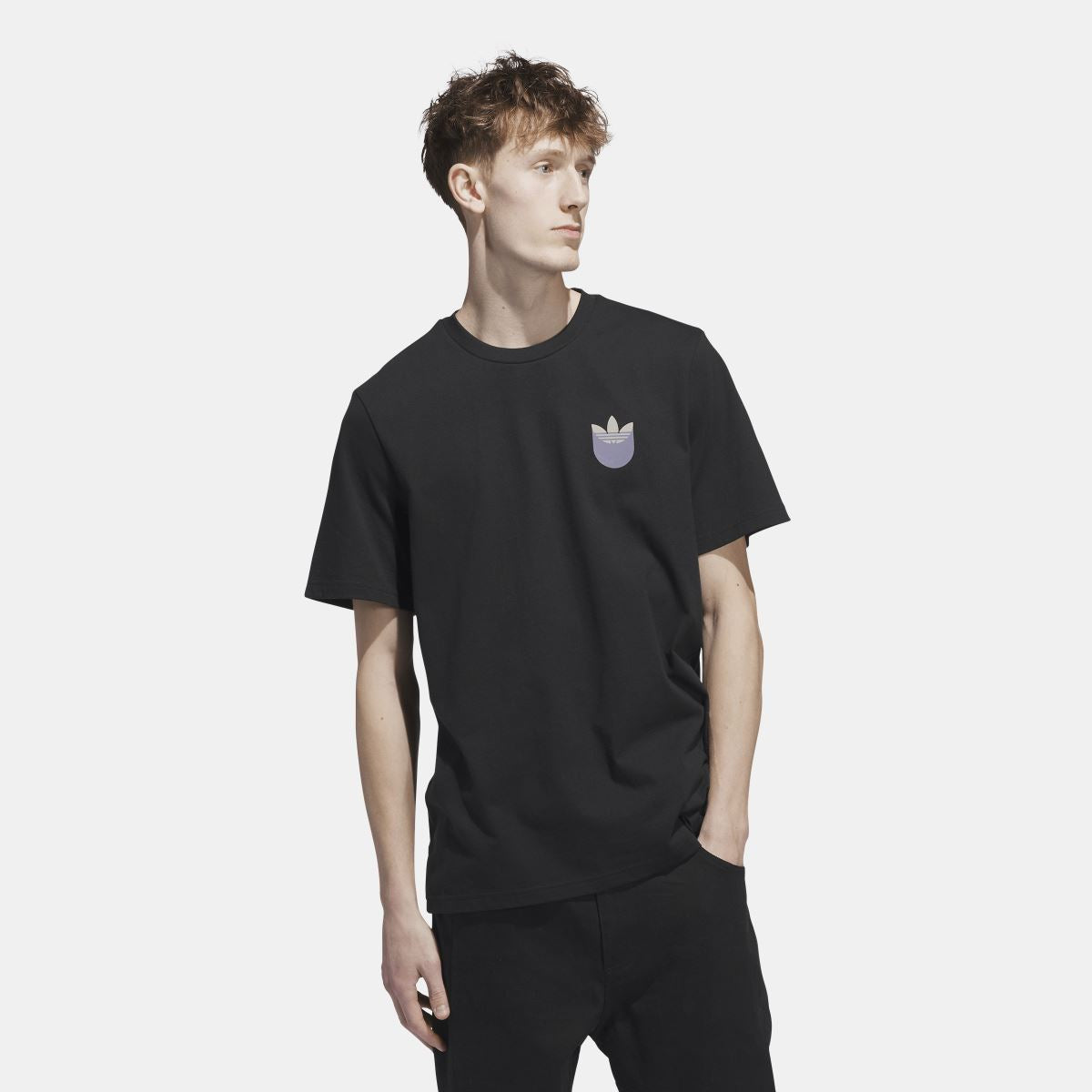Black t-shirt on model with small trefoil shadow logo at chest