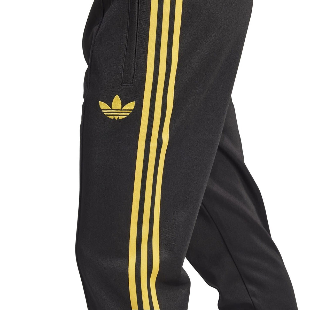 Black track pants detail with three vertical yellow stripes and yellow trefoil logo on leg