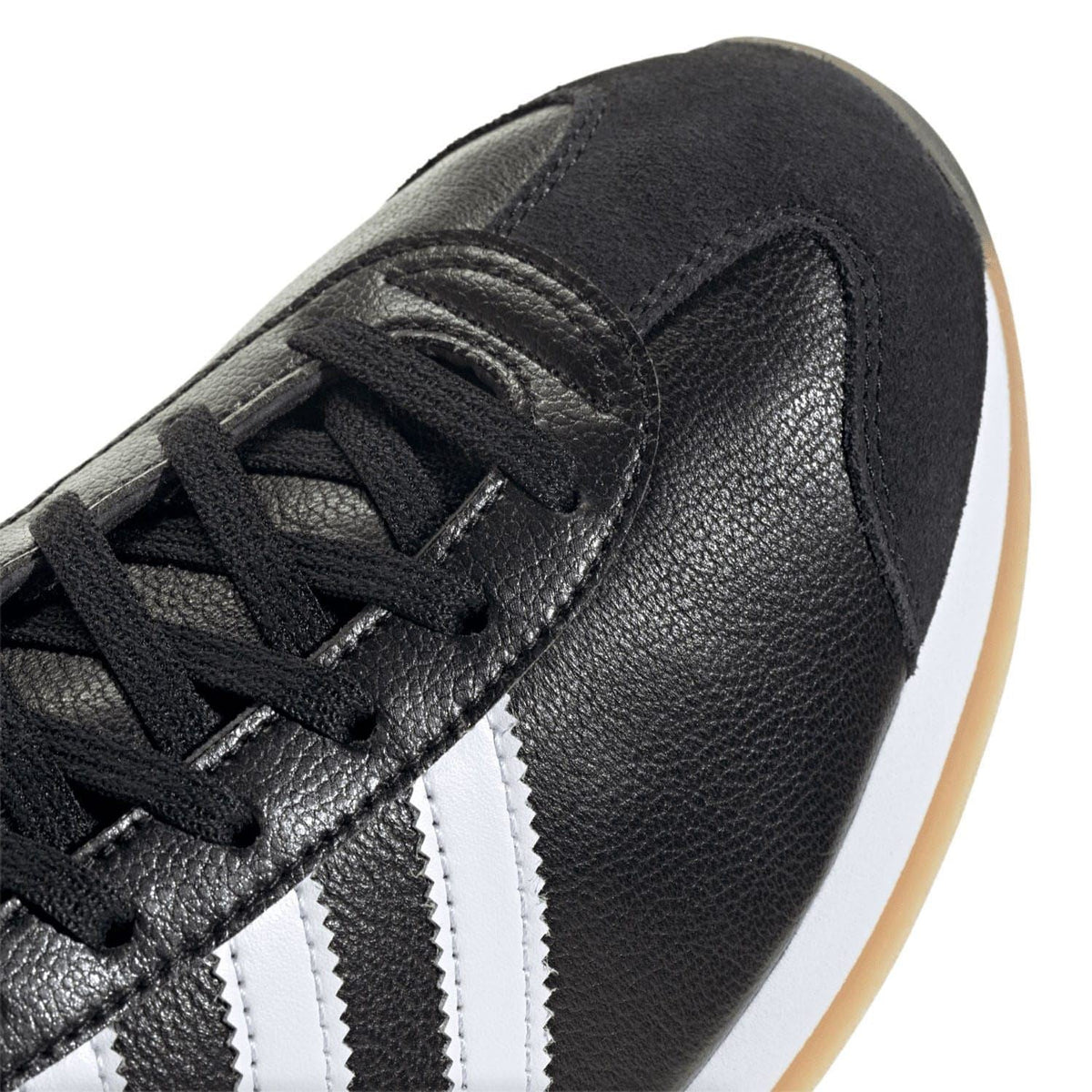 Close-up of black leather adidas trainers with white three stripes and lace