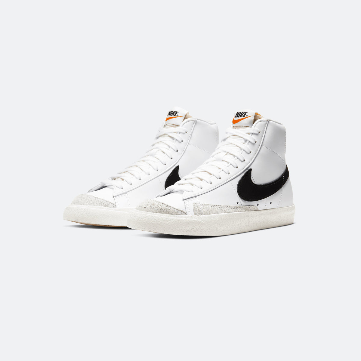 Pair of white Nike Blazer Mid '77 sneakers with black swoosh and cream outsoles
