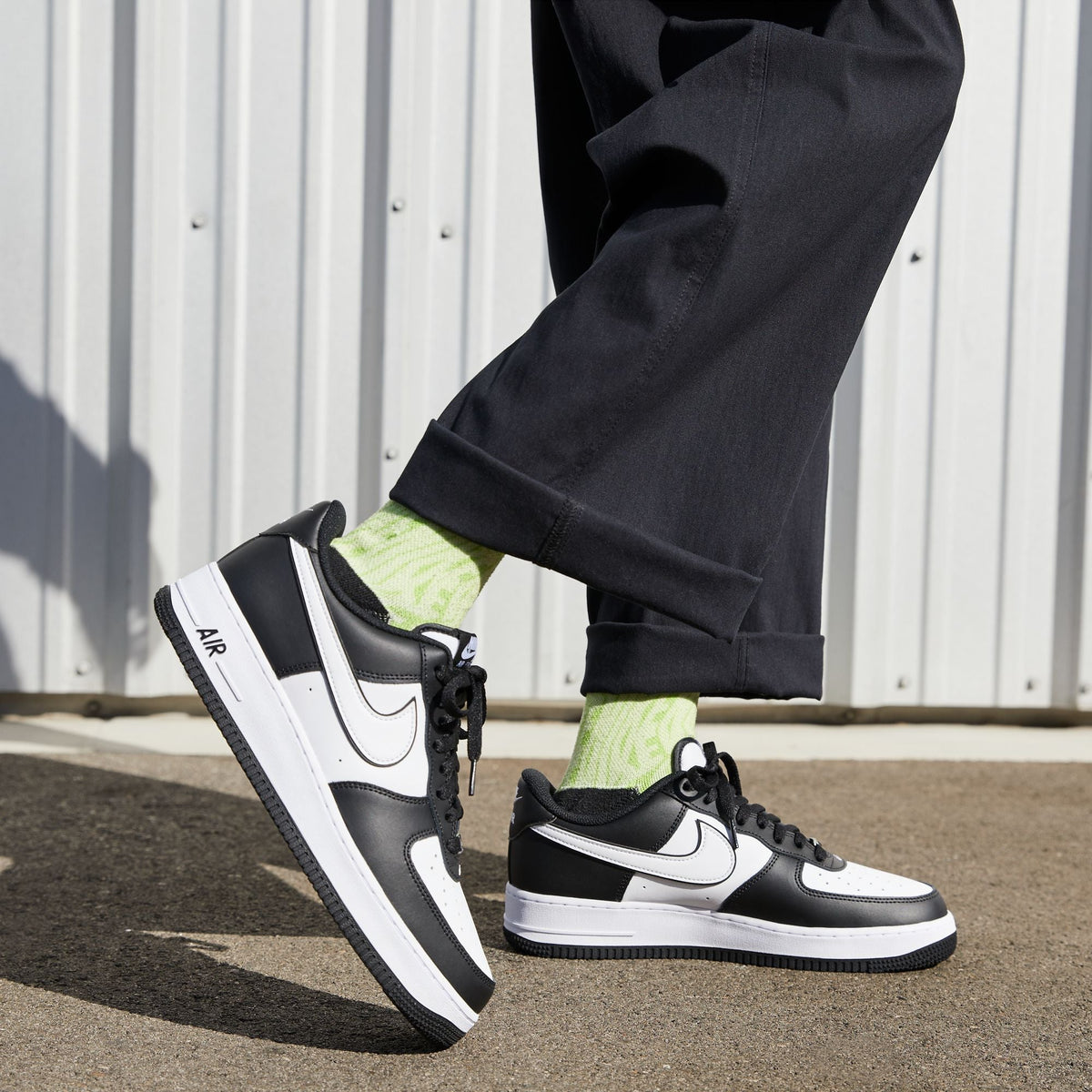 Air Force 1 '07 sneakers on model, worn with black pants and neon green crew socks