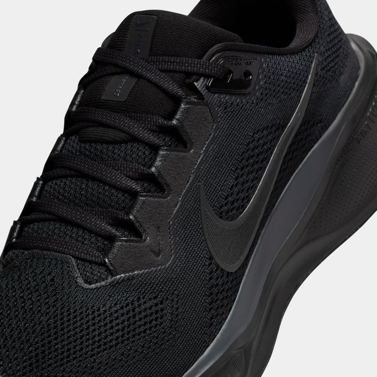 Black running shoe close-up of laces, mesh texture, and Nike swoosh on side
