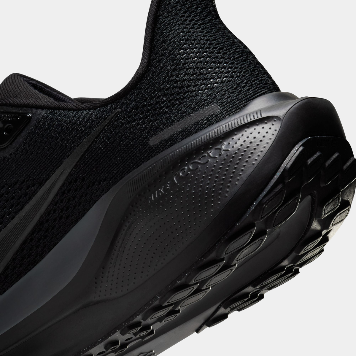 Black running shoe side close-up with perforated midfoot and molded outsole tread