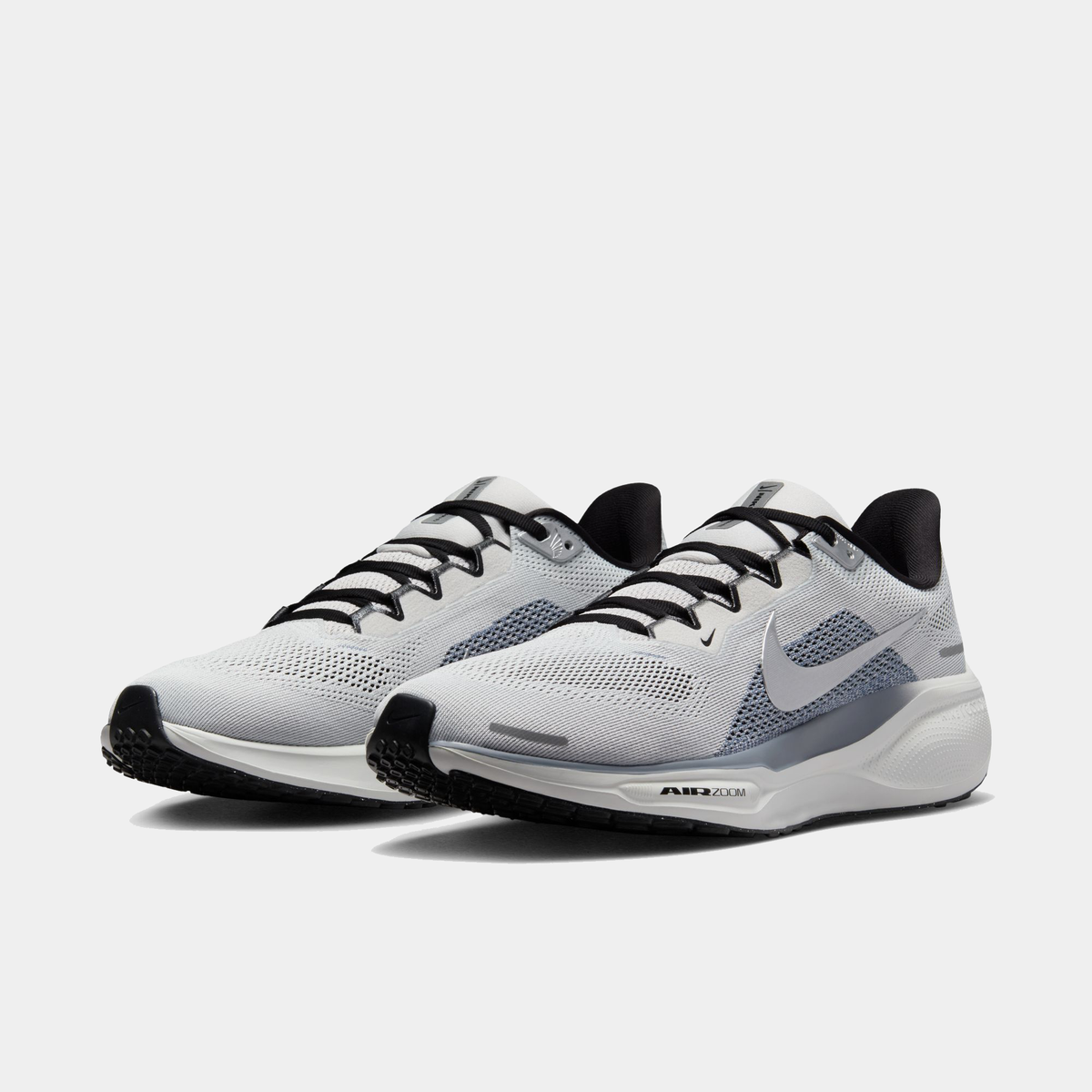 Pair of light gray running shoes with navy swoosh, black lace eyelets, and white midsole