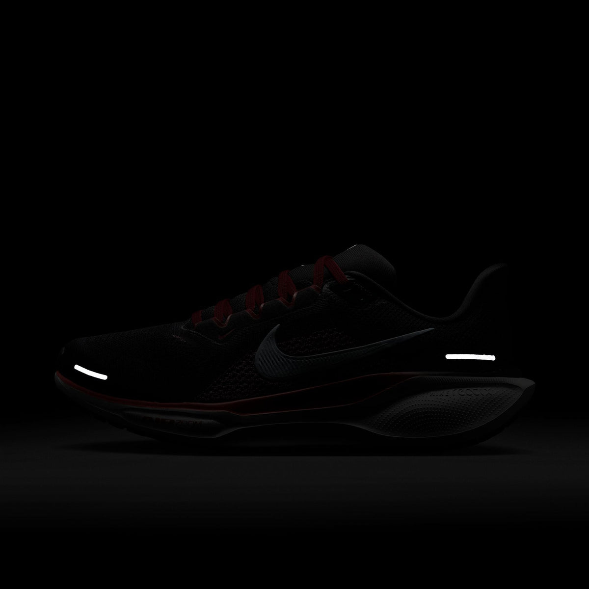 Black running shoe with Nike swoosh, red accent laces and side stripe