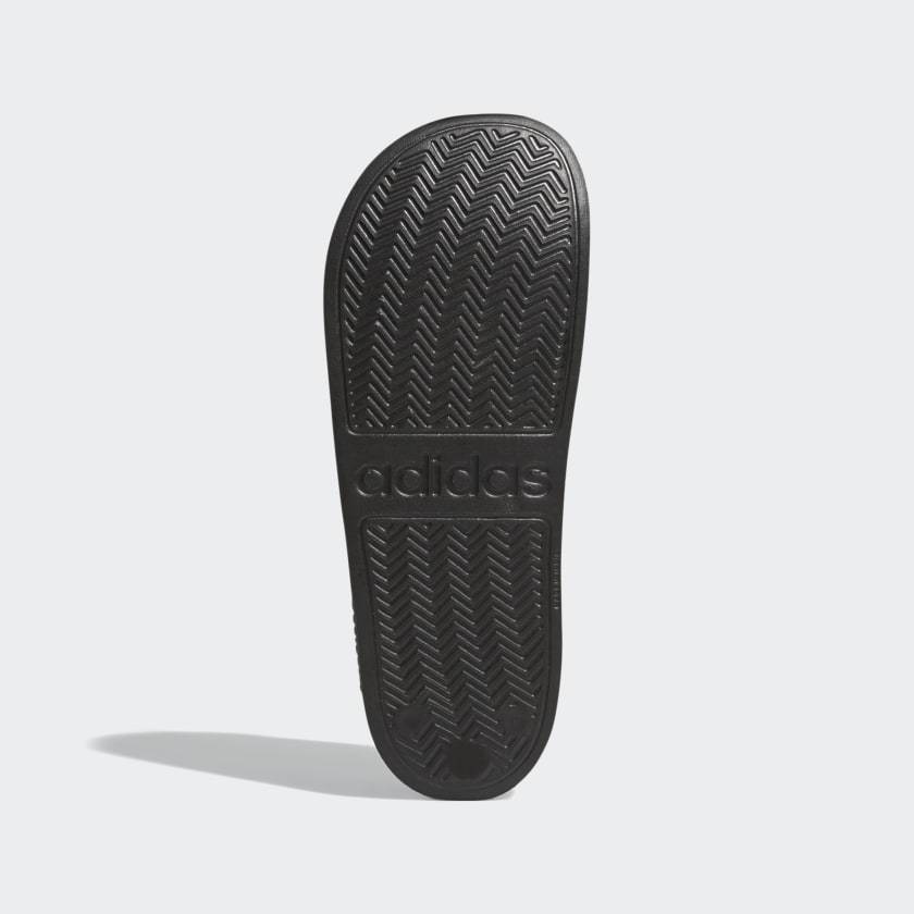 Black shower slide sandals outsole with textured herringbone tread and adidas branding