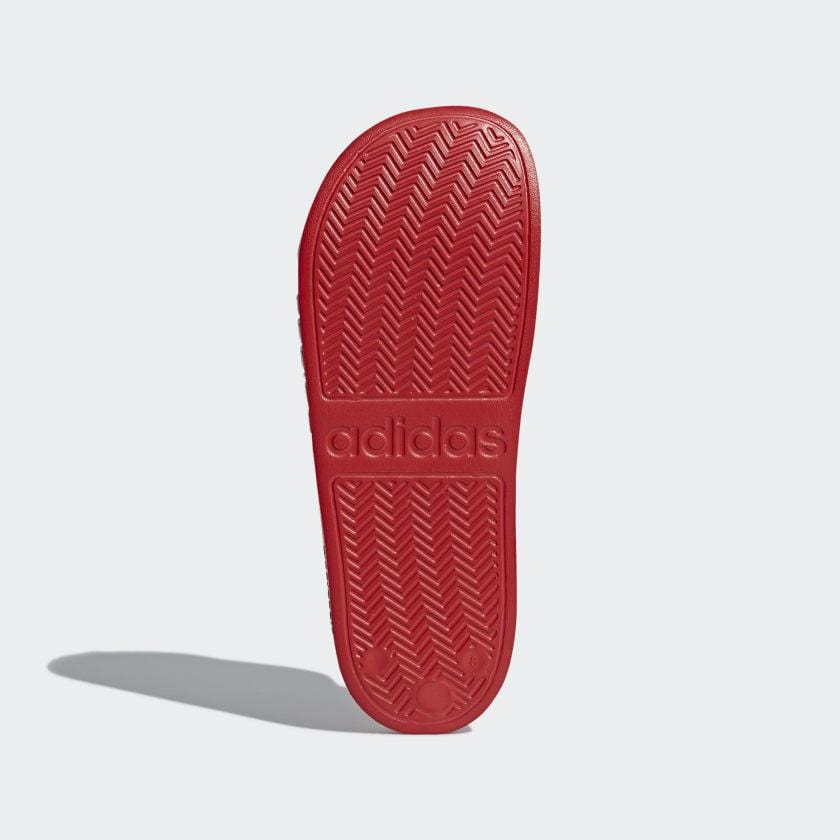 Red Adidas slide sandal outsole with textured chevron tread and adidas branding
