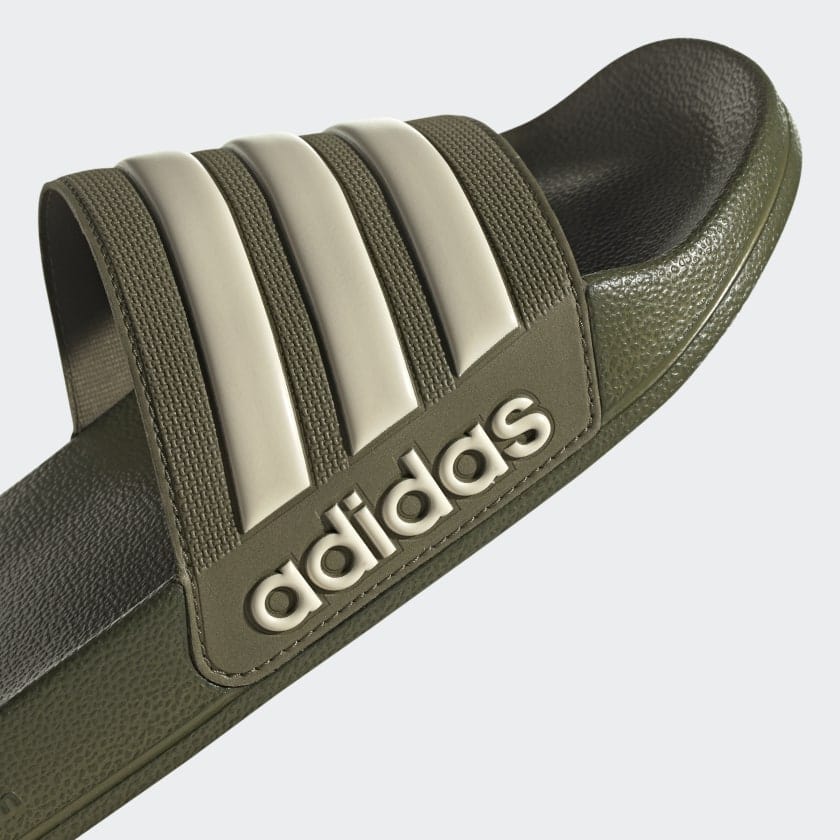 Olive slide sandal close-up: adidas logo on side, three white stripe bands