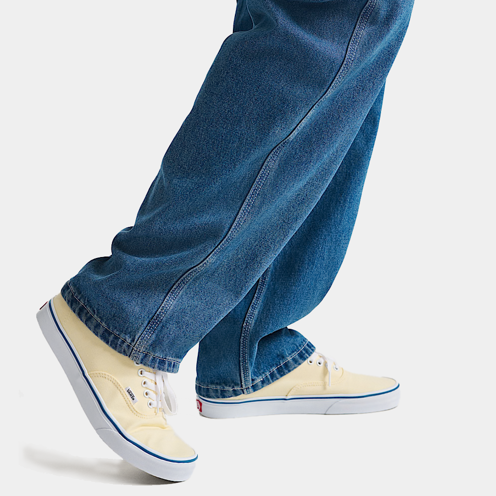 Cream sneakers with blue side stripe on denim jeans, low-top lace-up