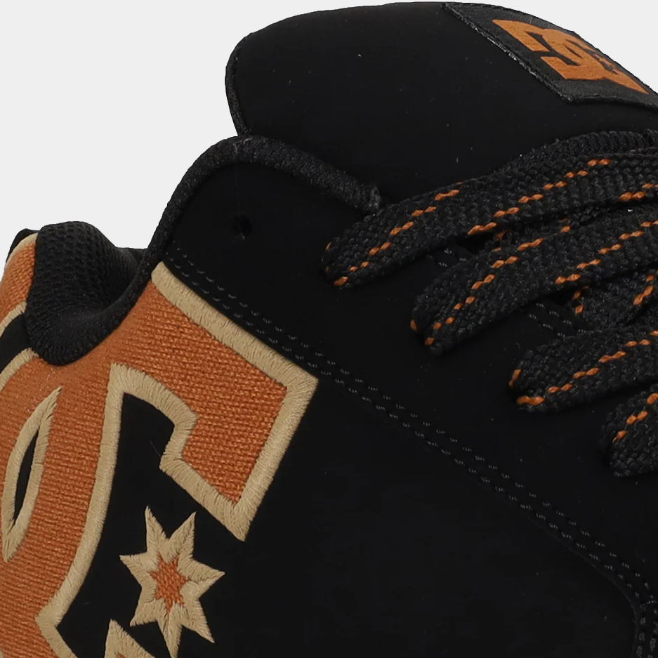 Close-up of black sneakers with tan star panel and orange-thread lace stitching