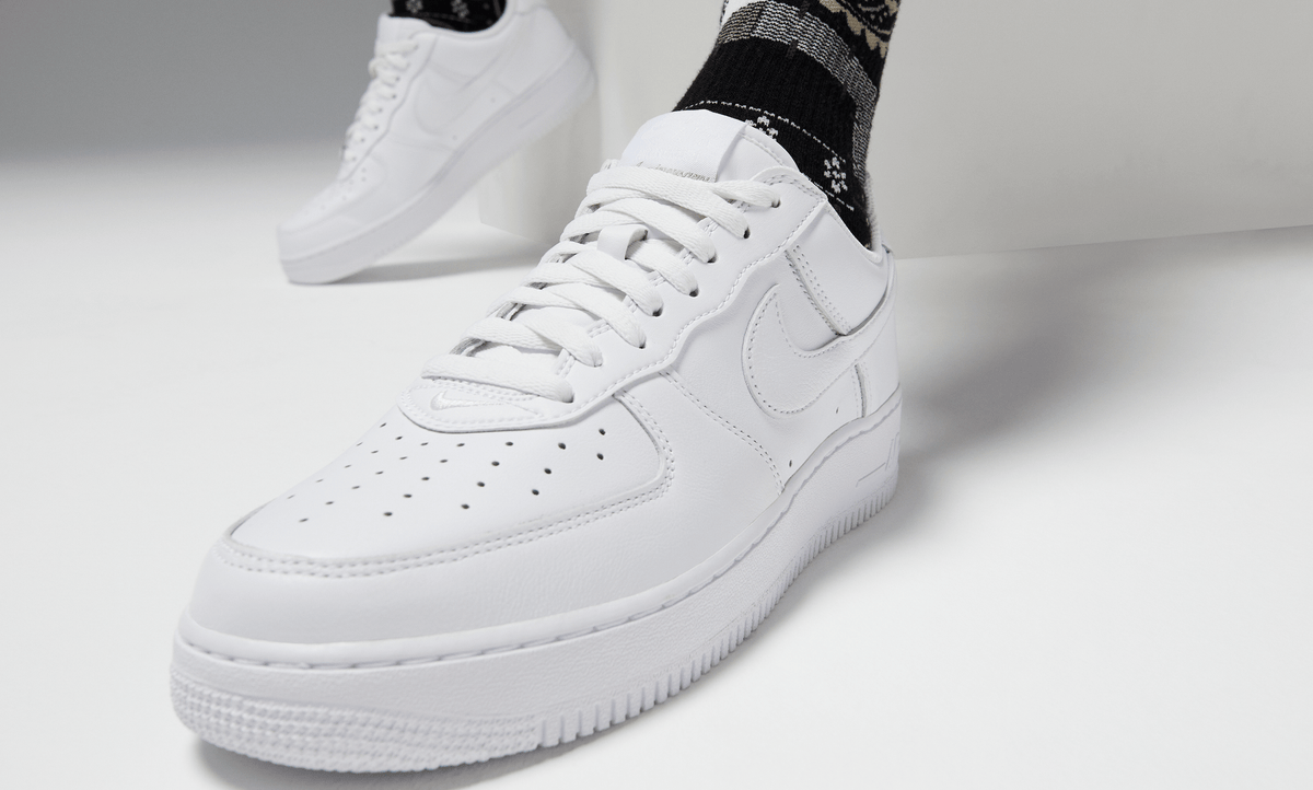 White lace-up sneakers with swoosh logo, worn with white socks
