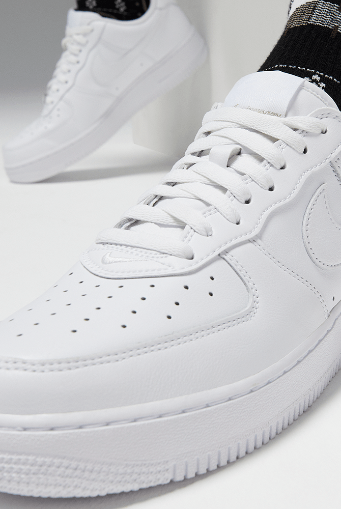 White lace-up sneakers with perforated toe and side swoosh