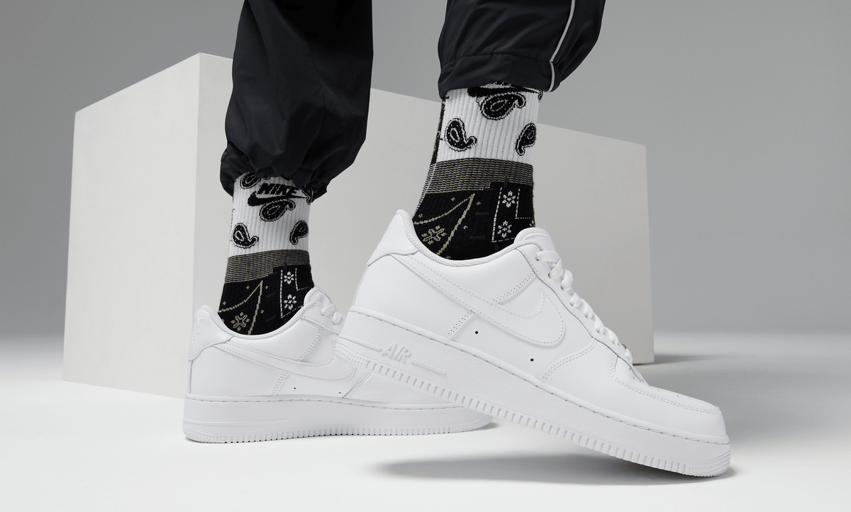 White low-top sneakers with black graphic patches, lace-up design