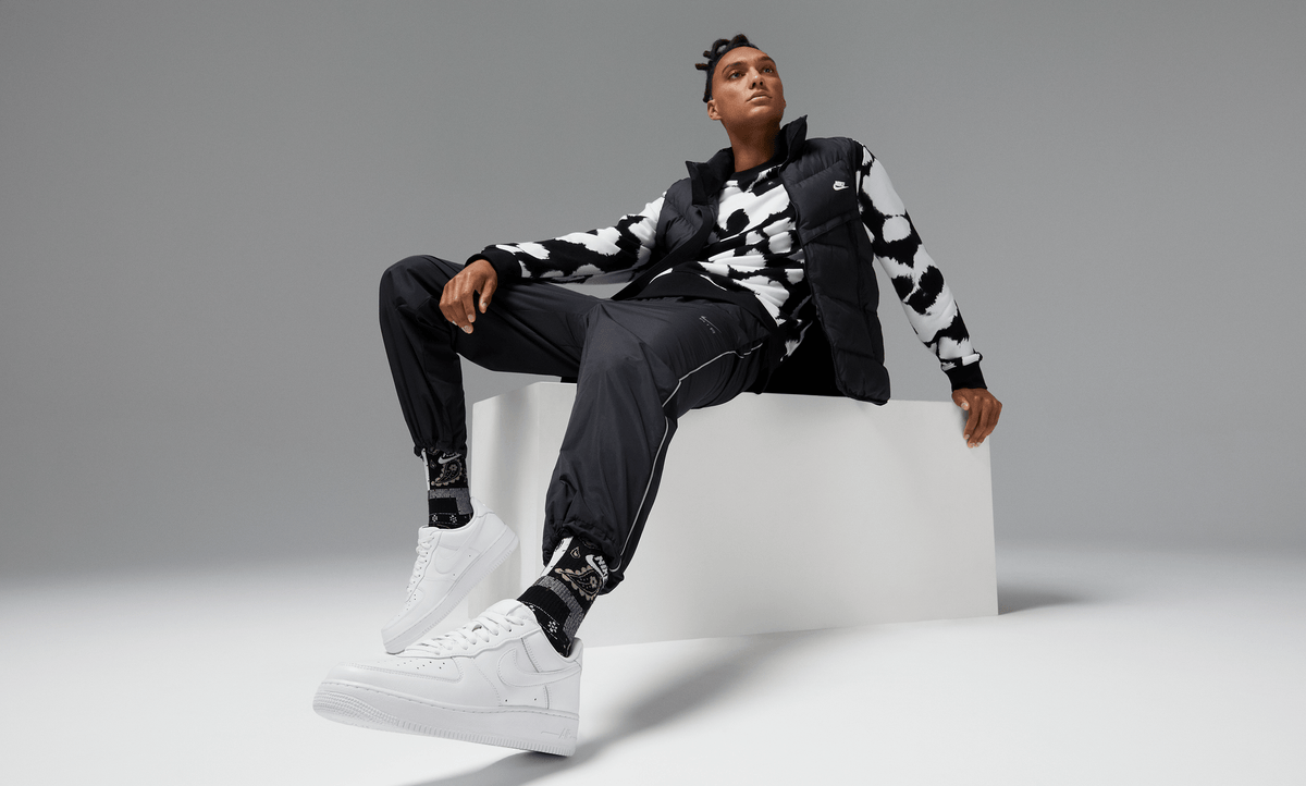 White low-top sneakers with lace-up front and swoosh logo while seated