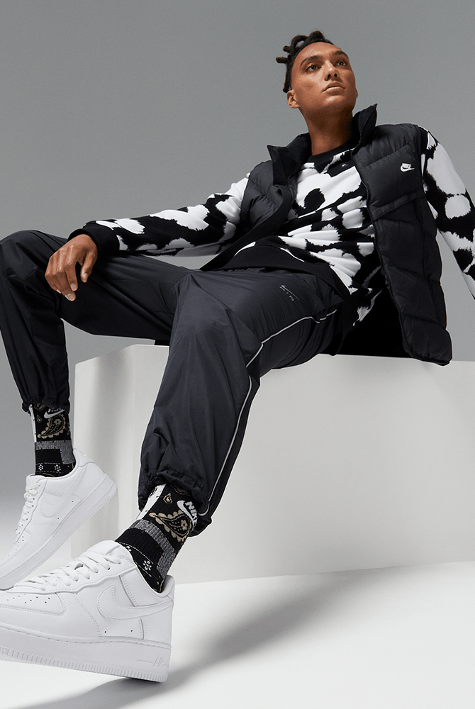 White lace-up sneakers on feet, with swoosh logo and thick rubber sole