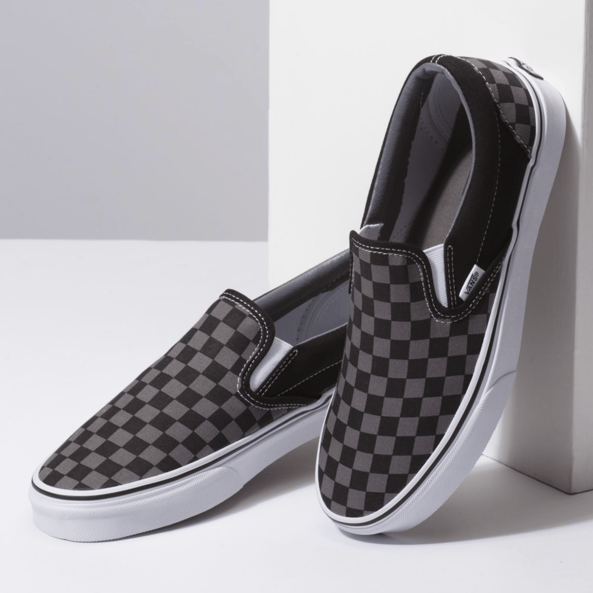 Black checkerboard slip-on Vans shoes with elastic collar and white sidewall sole