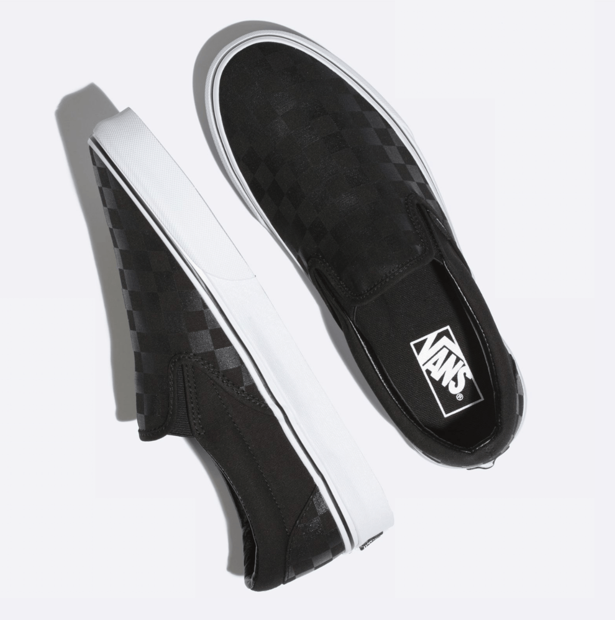 Black slip-on sneakers with checkerboard fabric and Vans logo on side