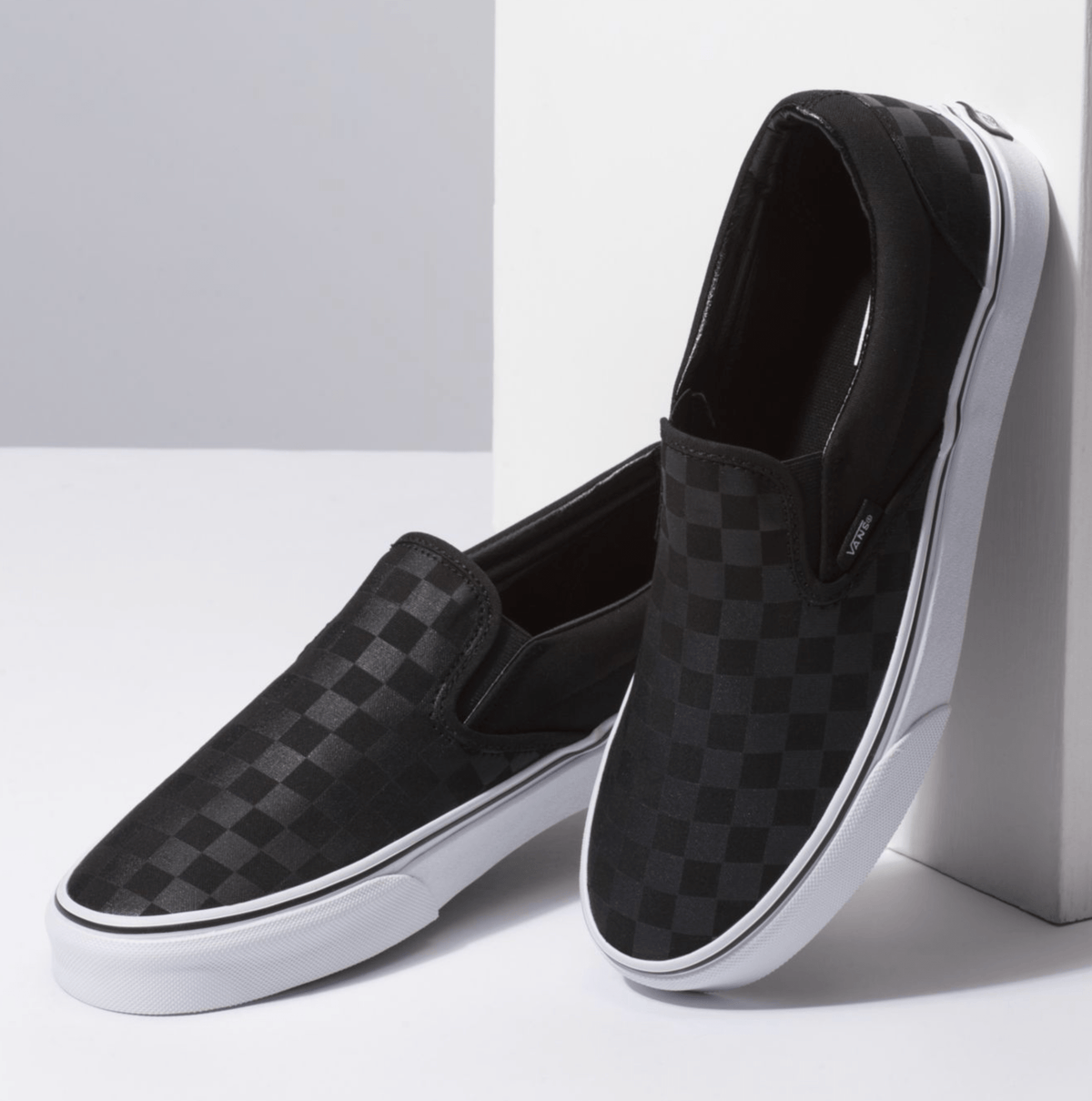 Black checkerboard slip-on sneakers with white sidewall and rubber sole
