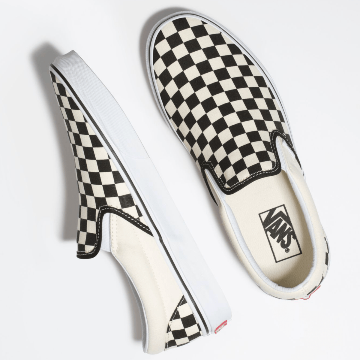 Black-and-white checkerboard slip-on sneakers with side stripe stitching and logo tag.