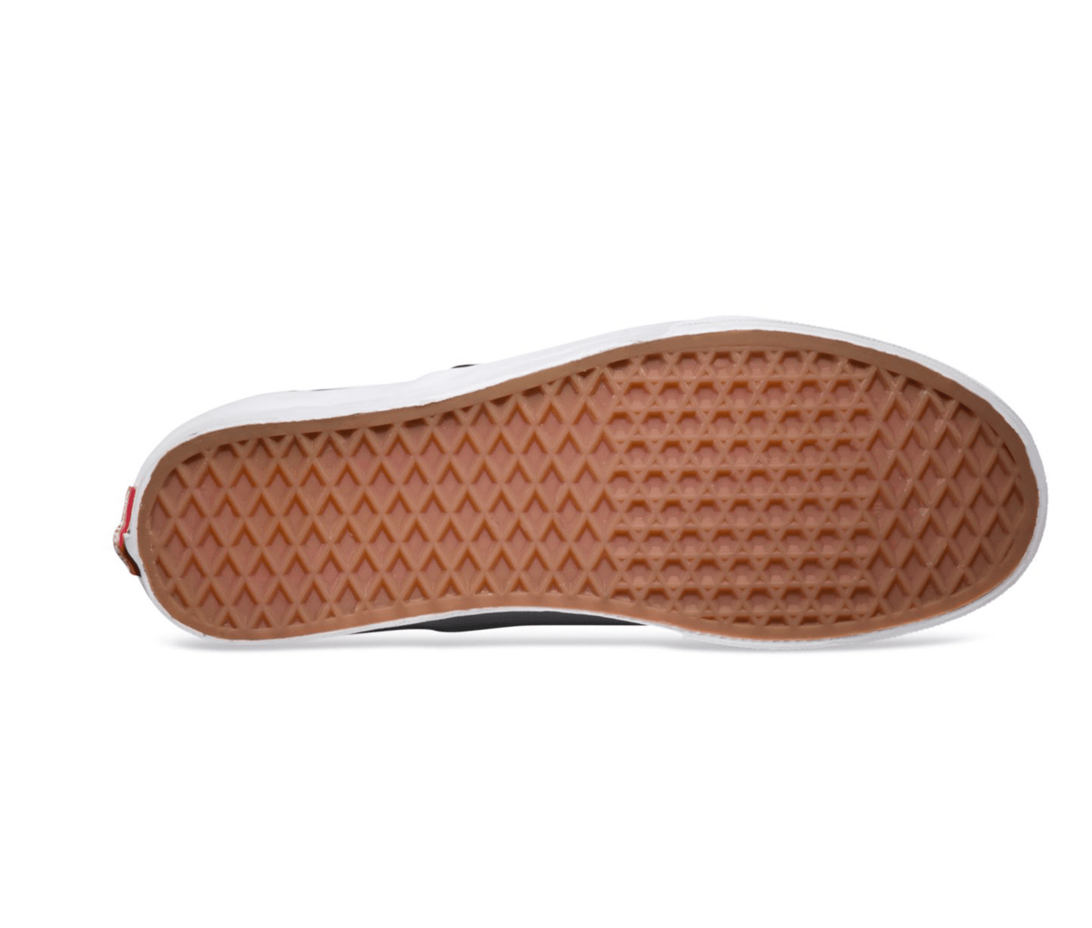 Bottom view of black-and-white checkerboard slip-on sneaker with textured rubber sole.