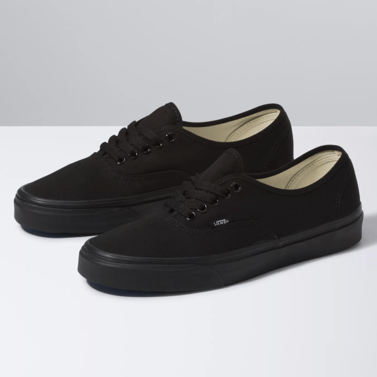 Black low-top lace sneakers with beige interior lining and black rubber sole