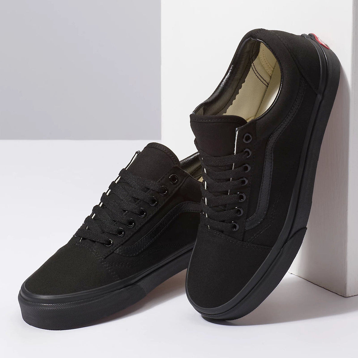 Black low-top sneakers with lace-up front, cushioned collar, and tan inner lining