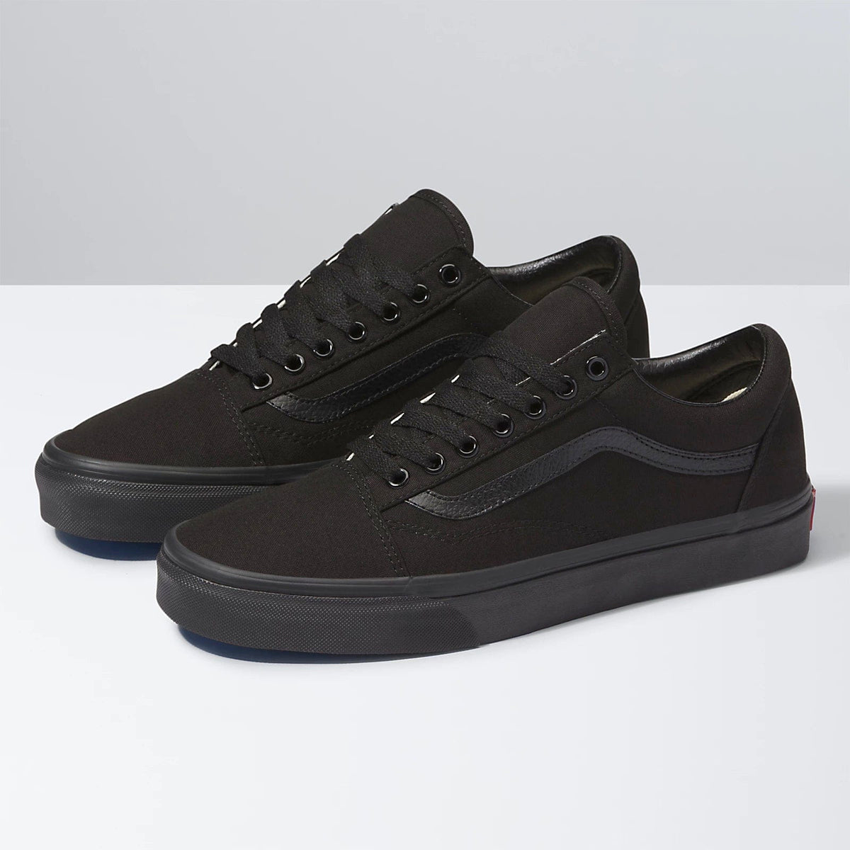 Black low-top sneakers with lace-up front, textured side stripe, and rubber sole