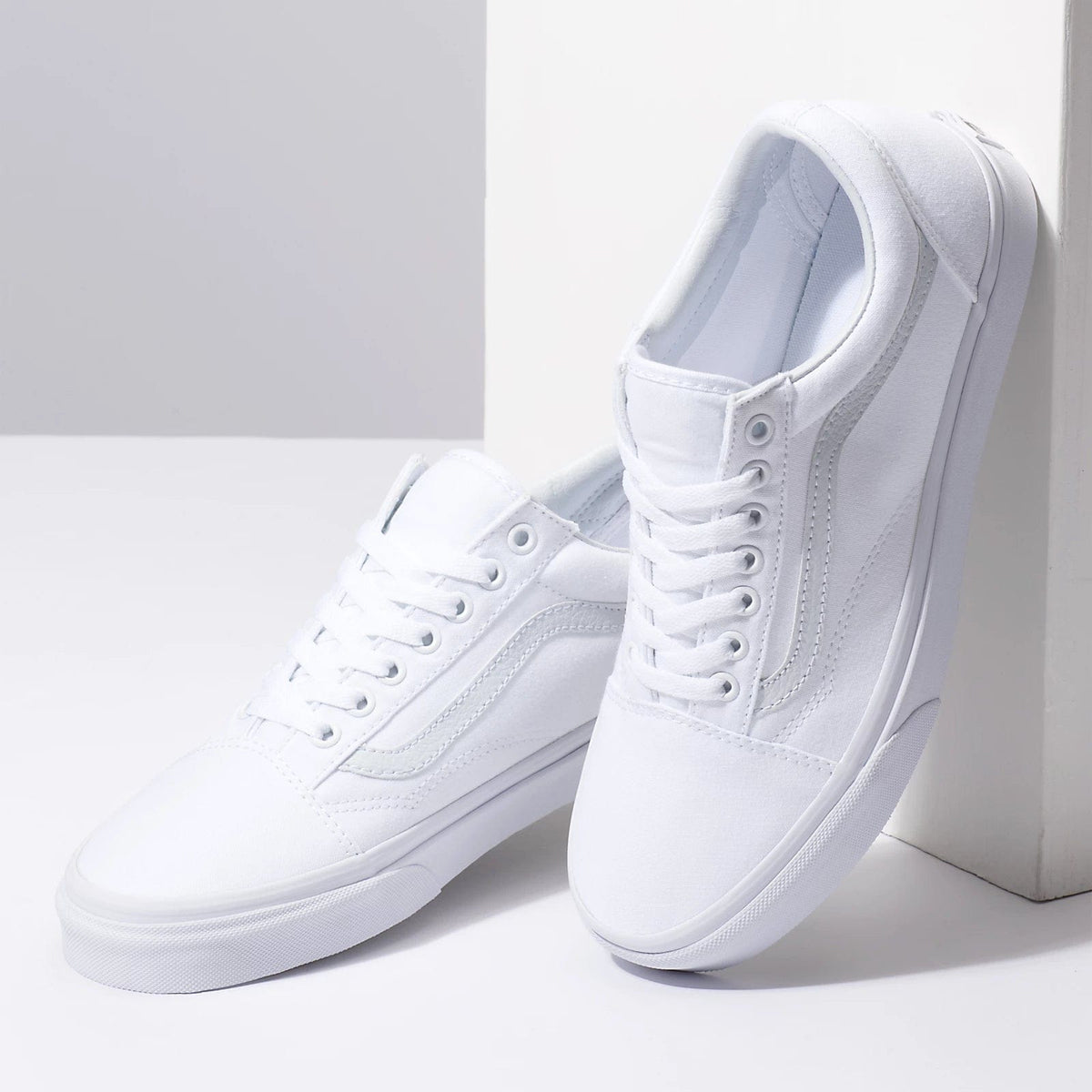 Pair of white low-top sneakers with lace-up front and padded ankle