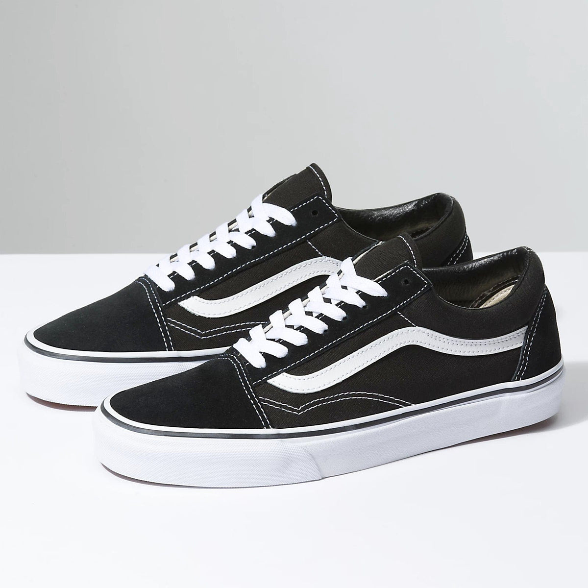Black low-top sneakers with white side stripe and white laces, flat rubber sole