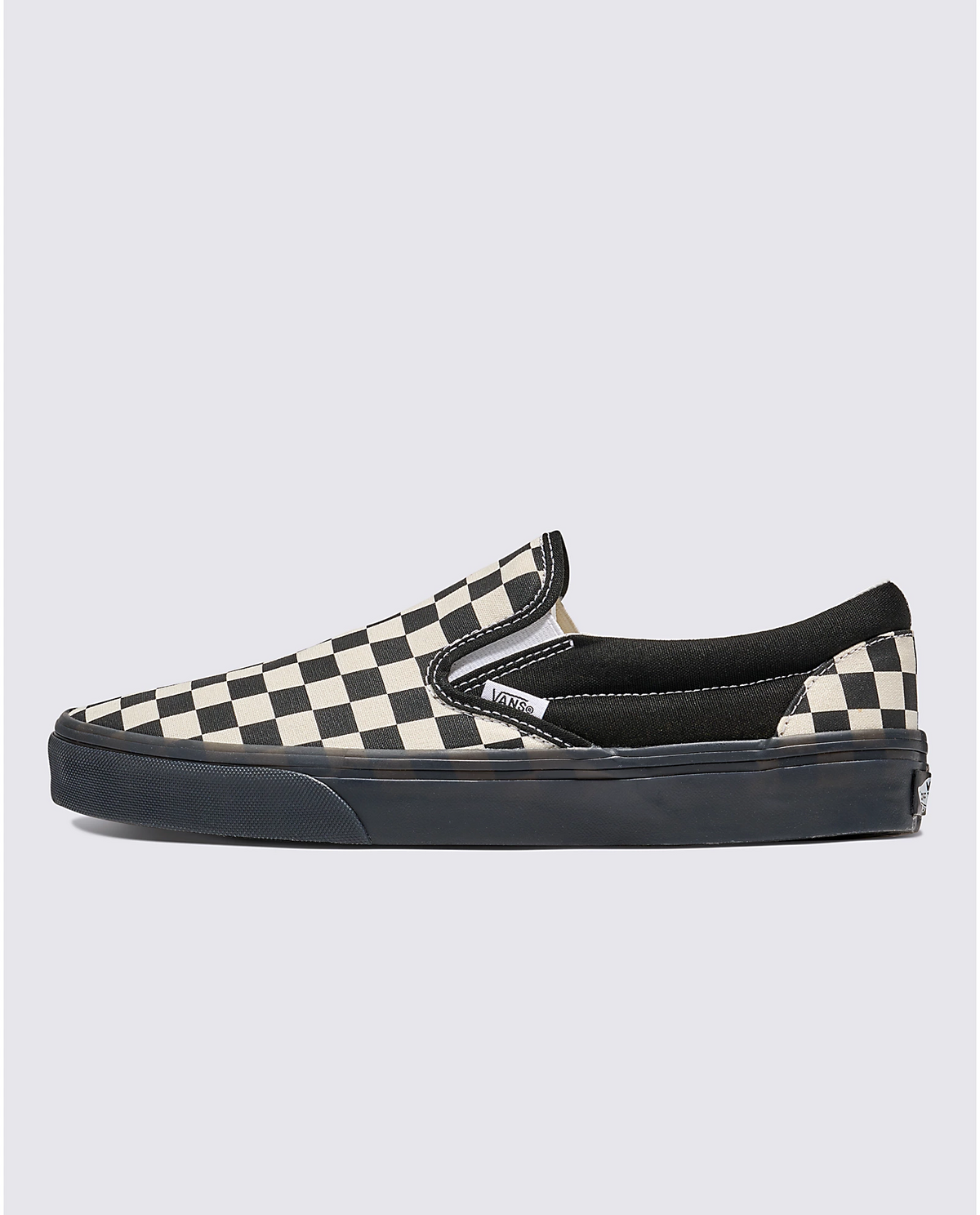 Side view of black-and-white checkerboard slip-on sneaker with dark outsole.