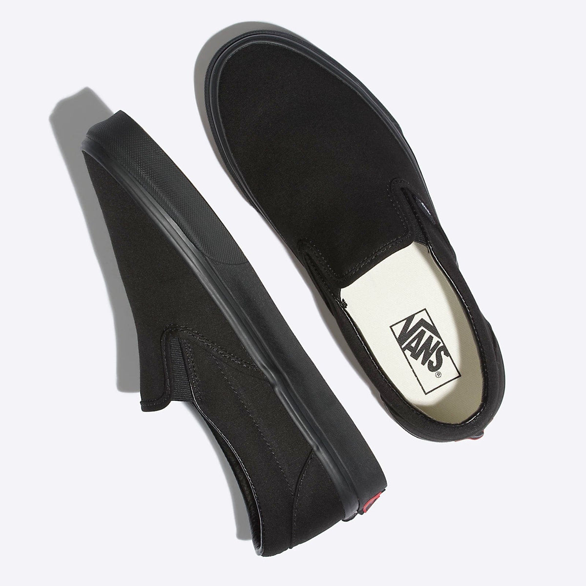 Black slip-on sneakers, side views, with Vans logo label on insole