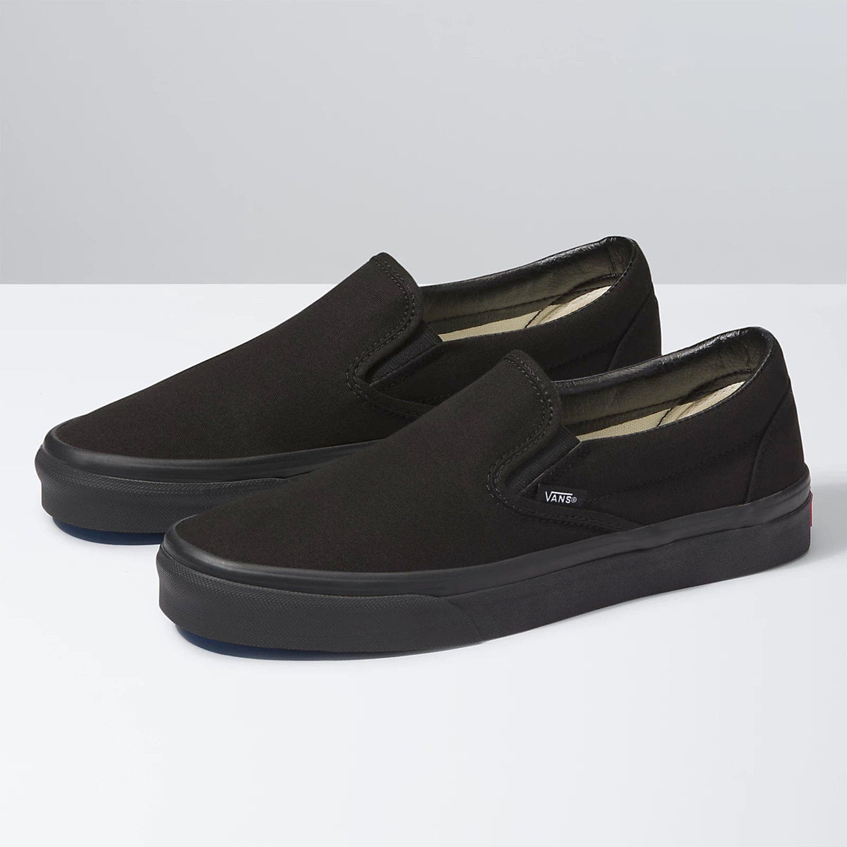 Black slip-on sneakers pair, angled side view, with dark rubber sole