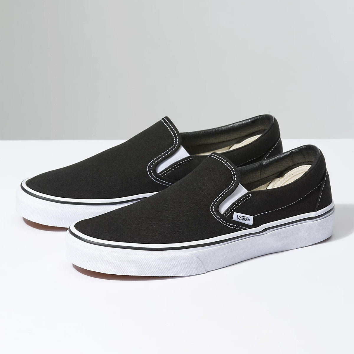Black slip-on sneaker with V-shaped side logo and white rubber sole