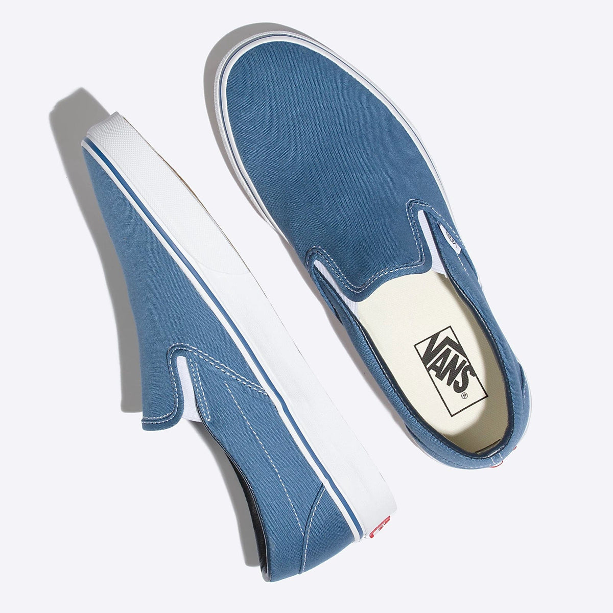 Blue slip-on sneaker pair angled view with Vans logo patch on beige insole