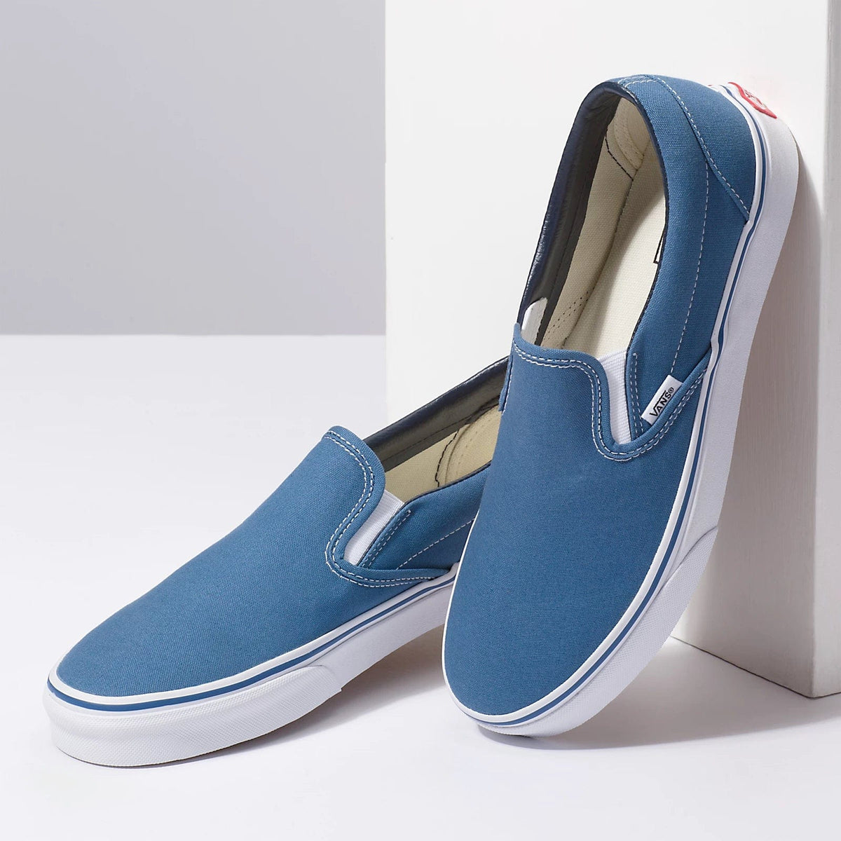 Blue canvas slip-on sneaker pair with white soles and padded side collar