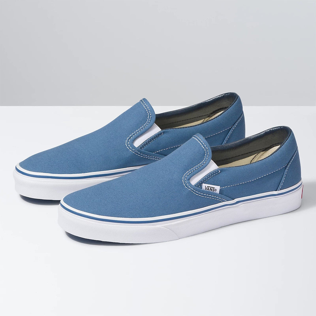 Blue canvas slip-on sneakers with padded collar and Vans logo patch on the side