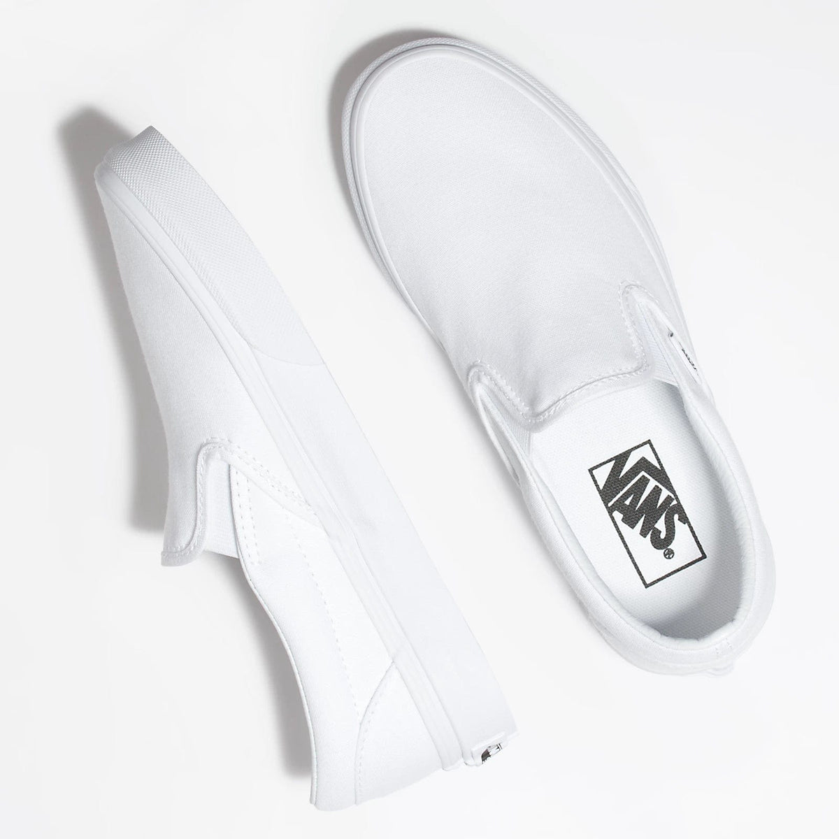 White slip-on sneakers showing side stitching and Vans logo on the upper