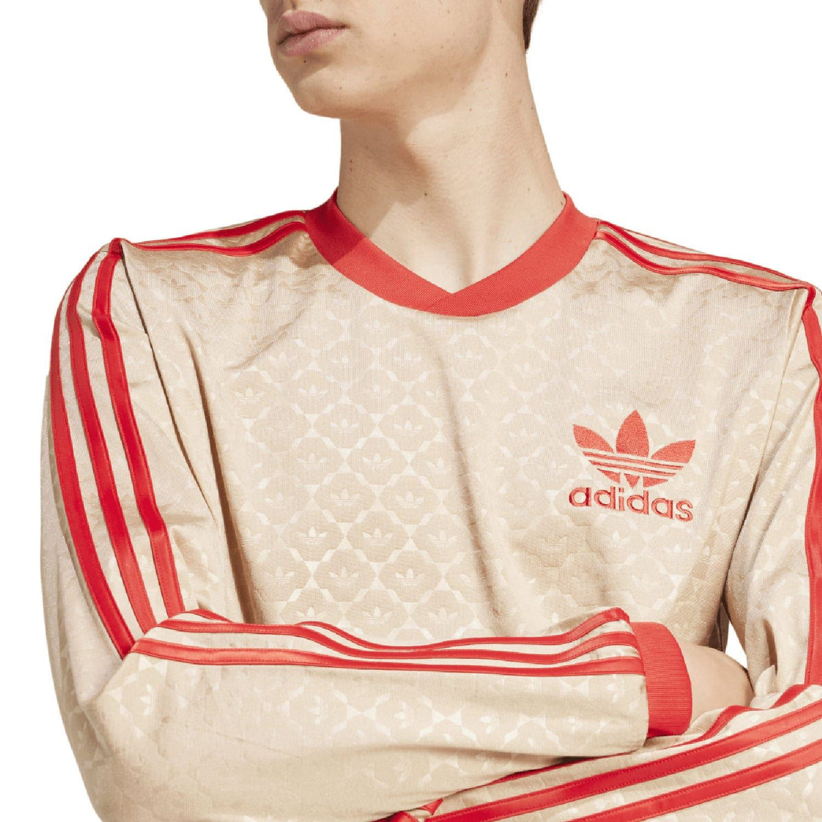 Close-up of beige adidas Originals jersey neckline, logo, and red three-stripe sleeve detailing