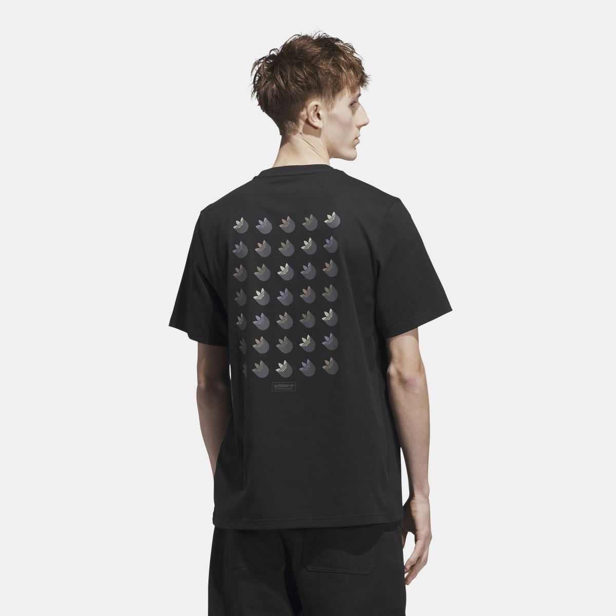 Black t-shirt on model with trefoil shadow logo pattern on back