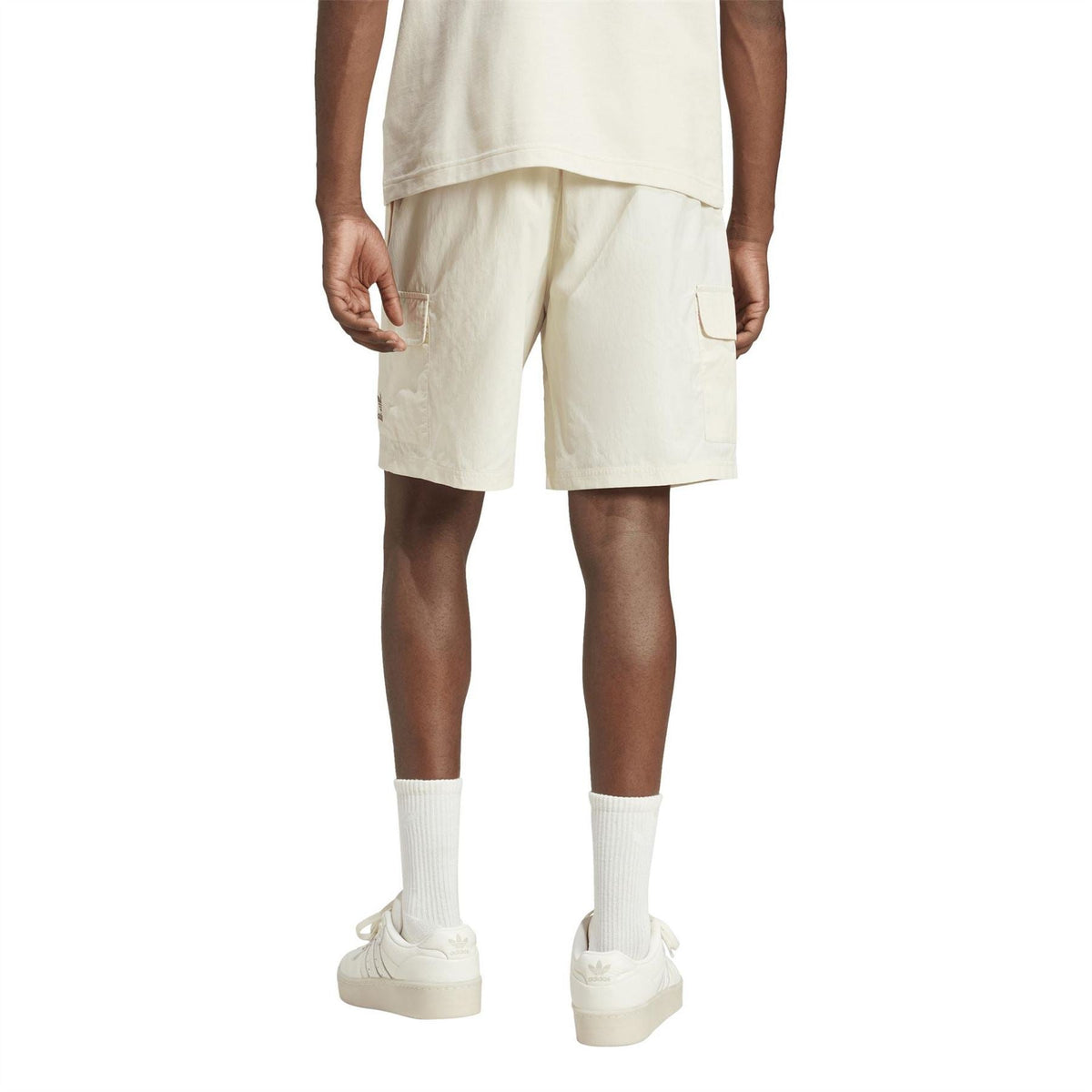 adidas Originals Essvn Shorts in black with white branding, featuring a relaxed fit and elastic waistband, displayed on a hanger.
