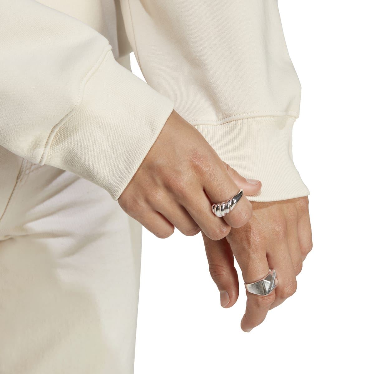 Cream sweatshirt sleeve cuff detail with ribbed hem and model hand.