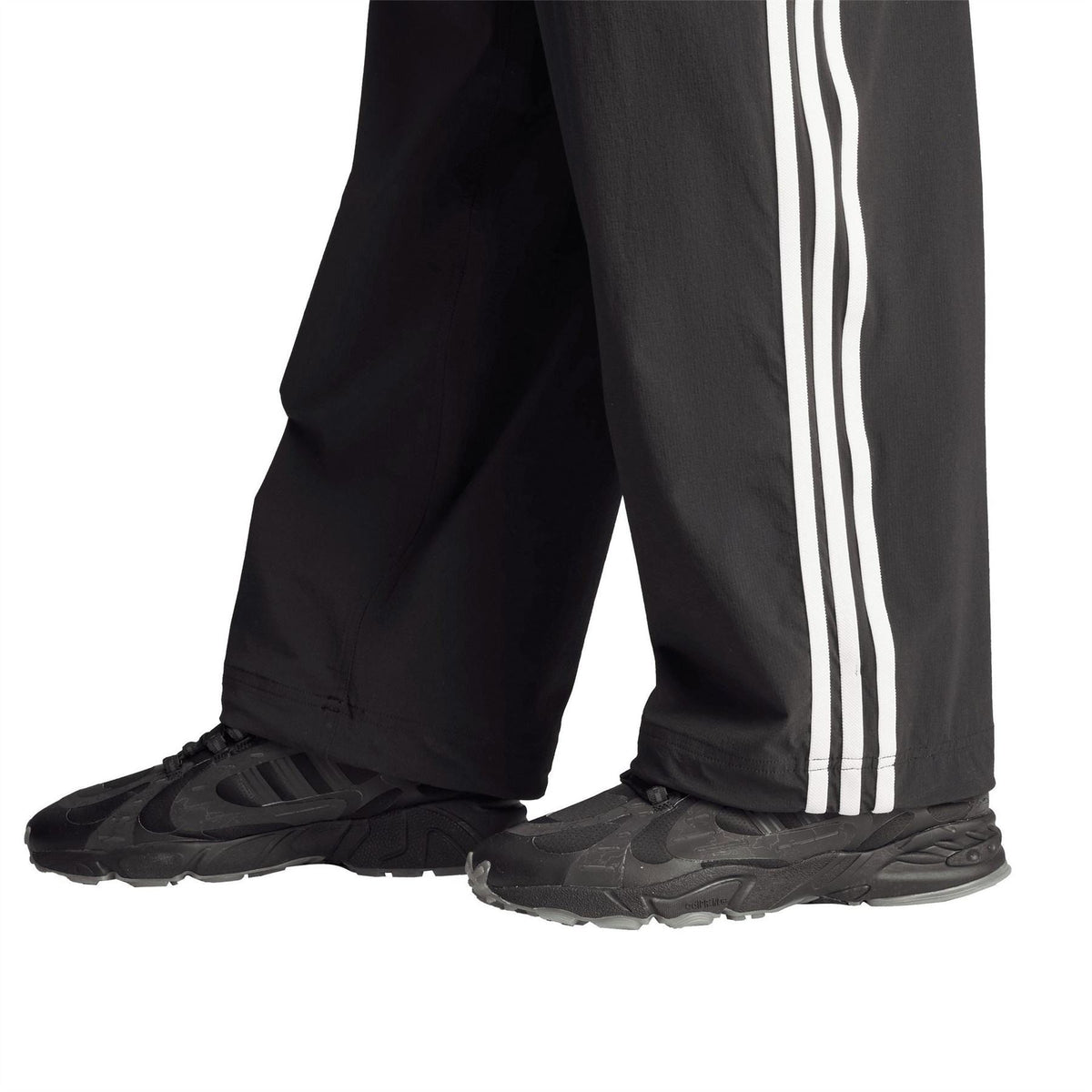 Black jogger pants lower legs with white stripes and athletic sneakers
